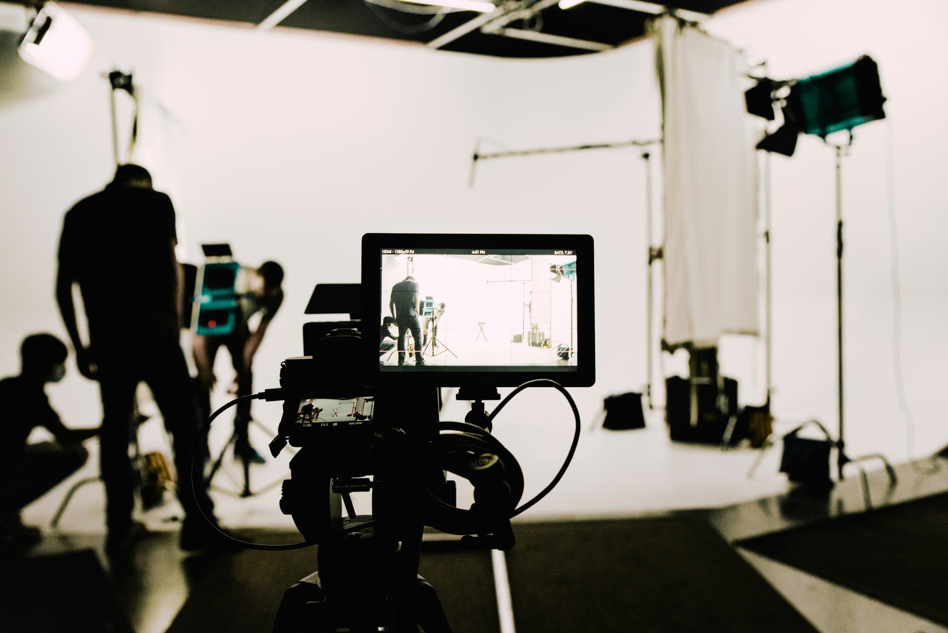 A traditional video shoot with a camera, monitor, studio lights and a crew